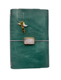 Emerald green leather journal with a rose quartz gemstone centerpiece and gold bookmark featuring a pink opal moon, evil eye charm, and “Spiritual Baddie” tag.