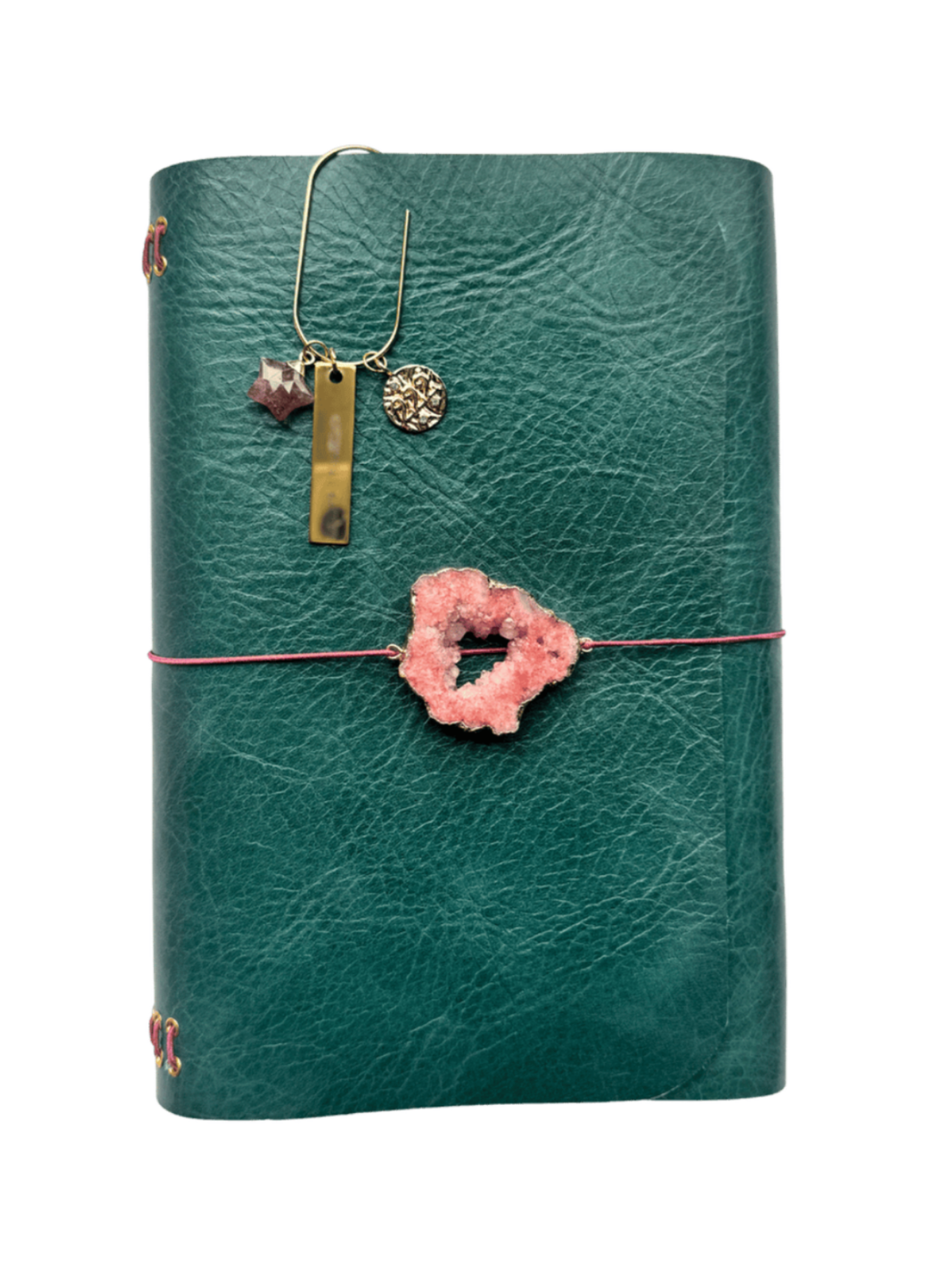 Green leather journal with a pink druzy geode talisman on the front and a gold bookmark featuring three charms: a star-shaped strawberry quartz, a “SPIRITUAL BADDIE” tag, and a round 222 charm.