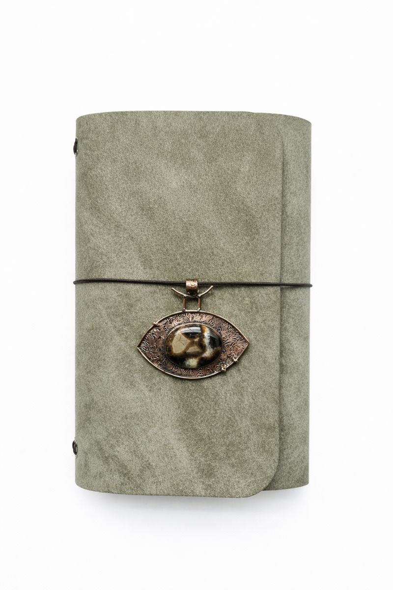 Veg tan leather grey with olive tone Pueblo finish tri fold journal with a gold pendant featuring Eye-shaped copper bezel set with an oval rose-cut Septarian
