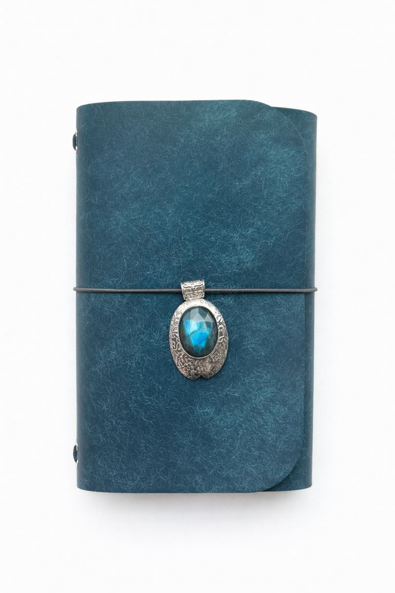 Cosmic Gatekeeper Mini Ritual A6 Journal - navy veg tan matte leather journal with smoky grey cording and a vintage-style rose cut Labradorite gemstone in carved silver-toned brass front charm.
